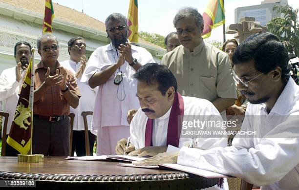 Sri Lankan Prime Minister Mahinda Rajapaksa (C) and Secretary of the Marxist JVP,(People's Liberation Front) Tilvin Silva (R) are applauded by officials as they sign an agreement in Colombo, 08 September 2005.   Rajapaksa signed a deal with the island's main Marxist party under which he agreed to drop plans to share power with Tiger rebels, but said he hoped the move will not lead to a resumption of war.  AFP PHOTO/Lakruwan WANNIARACHCHI (Photo by Lakruwan WANNIARACHCHI / AFP) (Photo by LAKRUWAN WANNIARACHCHI/AFP via Getty Images)